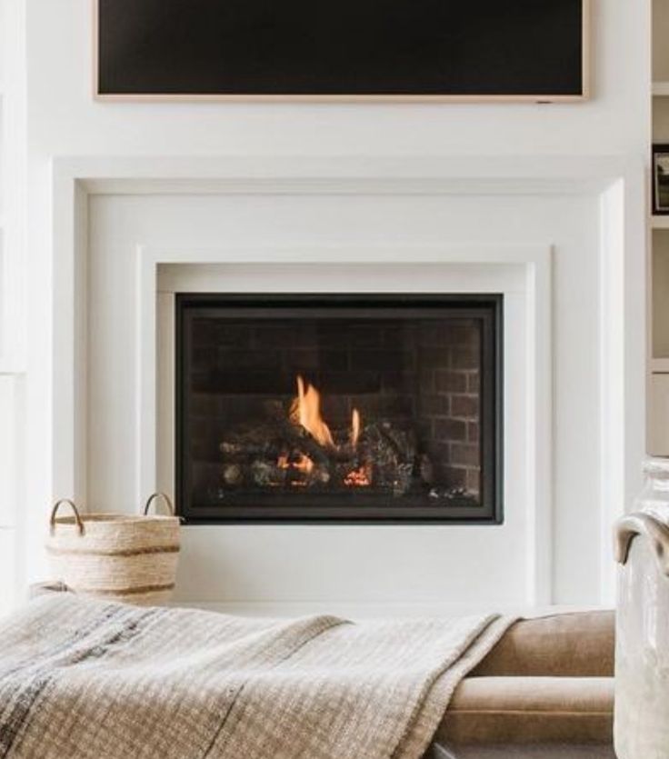 a living room with a fire place next to a book shelf and a blanket on the floor