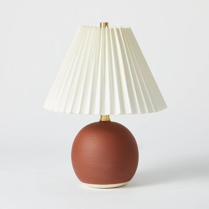 a brown lamp with a white shade on it's base and a light bulb in the middle