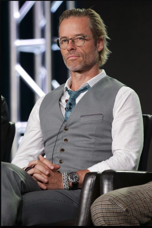 a man sitting in a chair with his hands crossed and looking at the camera while wearing glasses