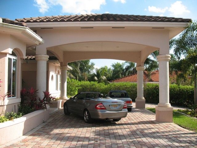 a car is parked in front of a house with columns and pillars on the driveway