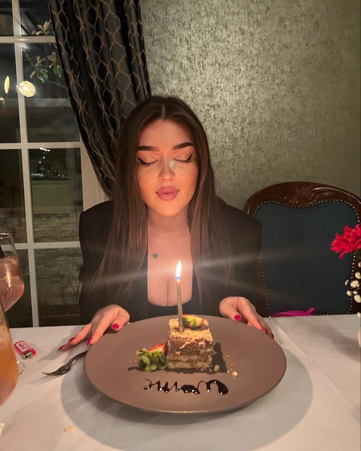 a woman sitting at a table in front of a plate with a cake on it