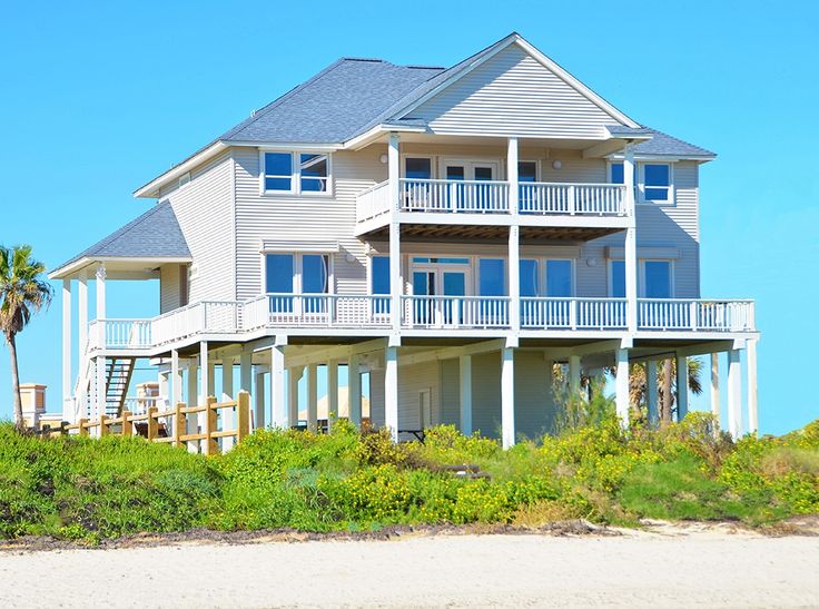 a large white house sitting on top of a sandy beach