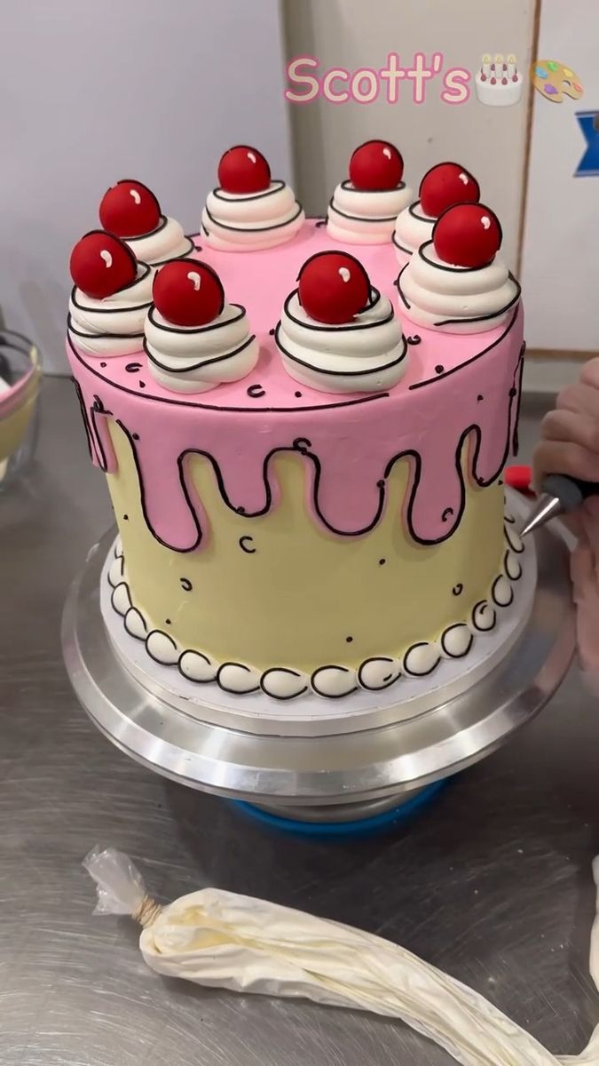 a pink and white cake with cherries on top is being cut by a person