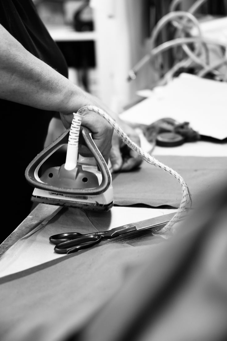 a person ironing fabric with scissors and other items on the table behind them in black and white