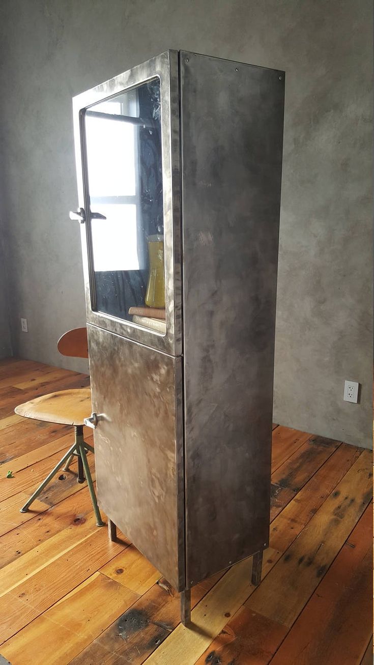 a metal refrigerator sitting on top of a wooden floor next to a table and chair