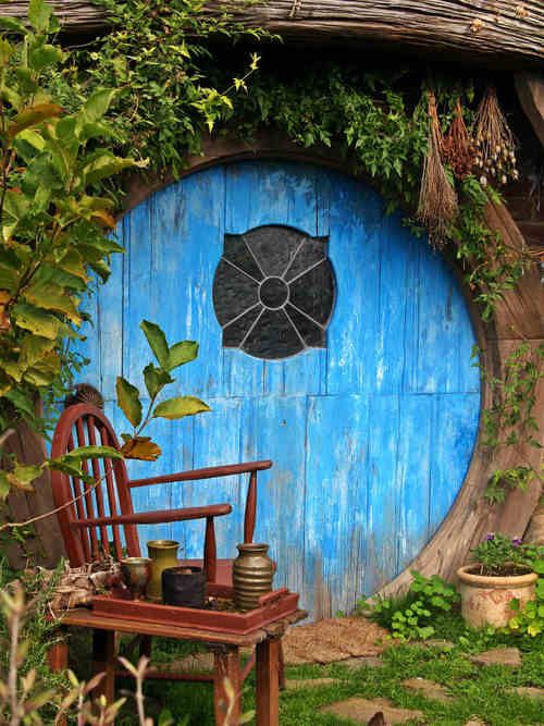 a wooden chair sitting in front of a blue hobbot with an umbrella on it