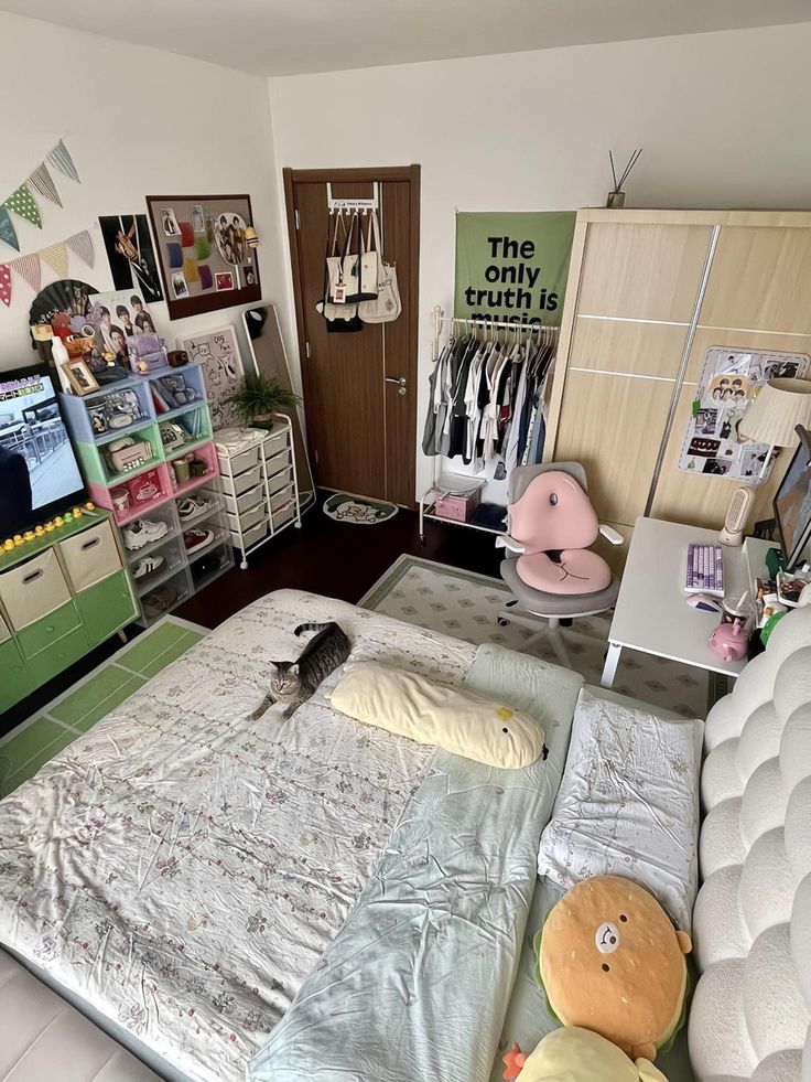 a bed room with a neatly made bed and lots of toys on the floor next to it