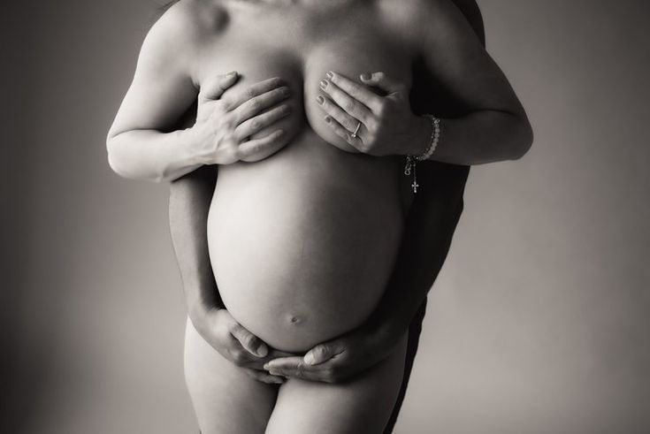 a pregnant woman is holding her hands on her stomach and posing for the camera in black and white