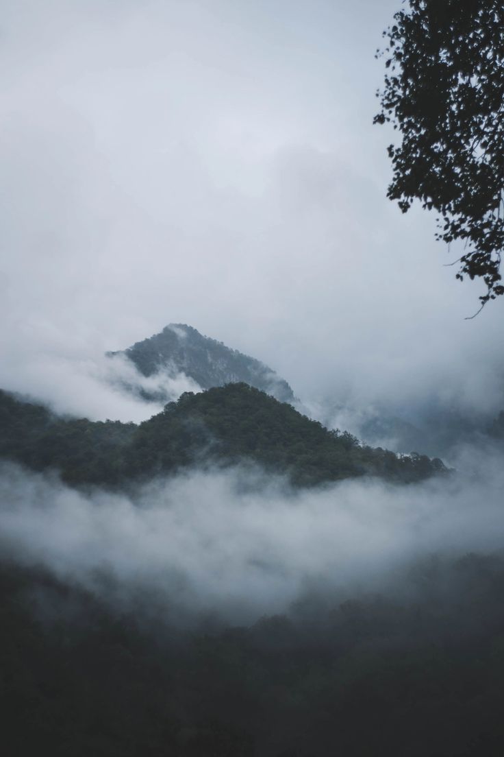 the mountains are covered in fog and low lying clouds