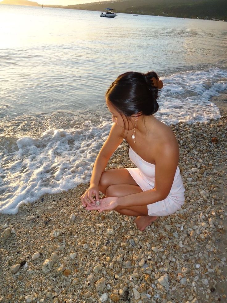 a woman sitting on top of a beach next to the ocean