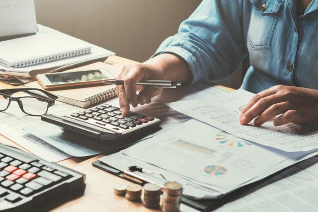 a person is using a calculator at a desk with papers and pencils