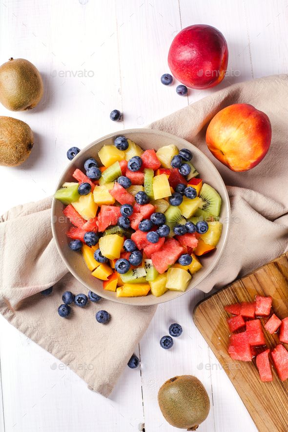 a bowl filled with fruit sitting on top of a wooden cutting board next to other fruits