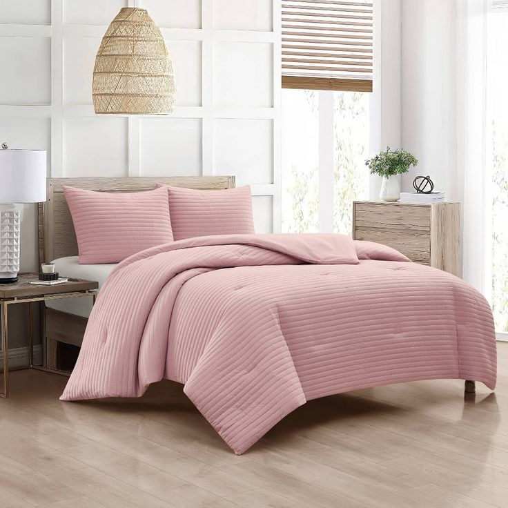 a bed with pink bedspread and pillows in a room