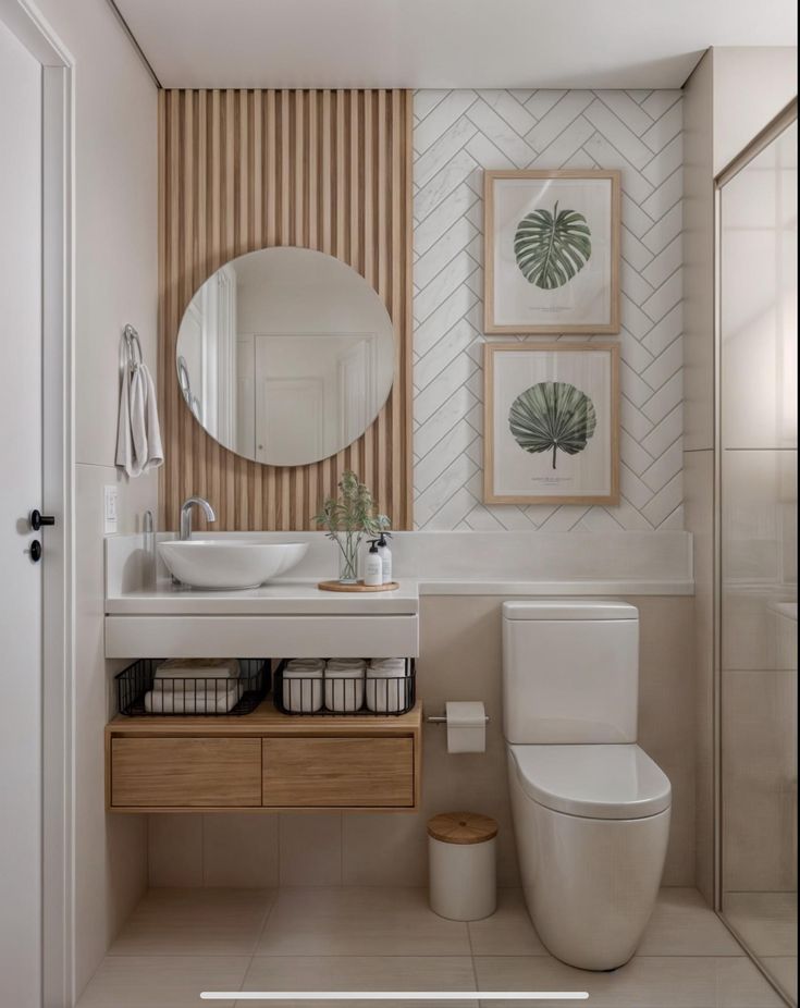 a white toilet sitting next to a bathroom sink under a round mirror on top of a wooden cabinet