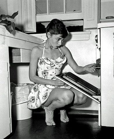 a young woman sitting on the floor in front of an oven