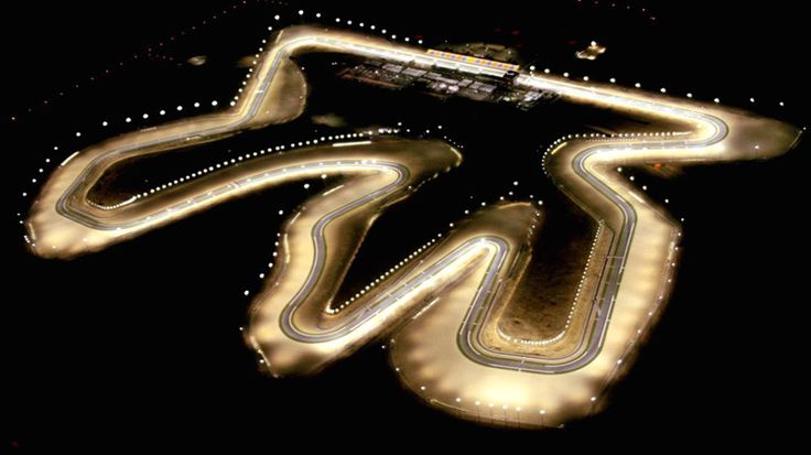 an aerial view of a race track at night with the lights turned on and winding