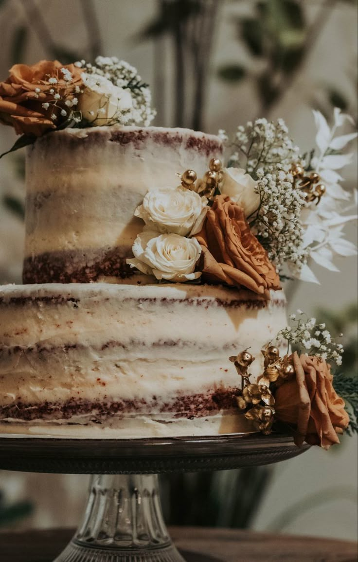 a three layer cake sitting on top of a wooden table next to white and orange flowers