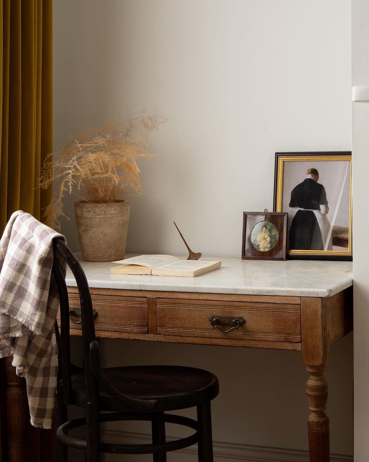 a desk with a book, potted plant and framed photograph