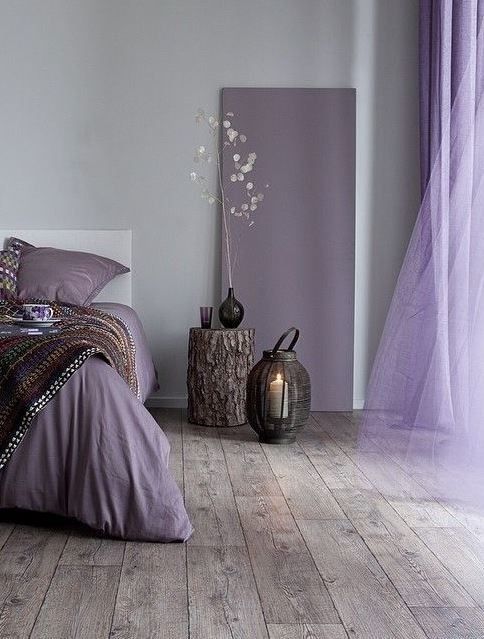 a bed room with a neatly made bed next to a window and a vase on the floor