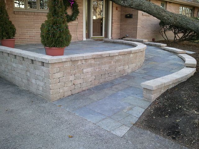 a brick patio with potted plants on the side and steps leading up to it