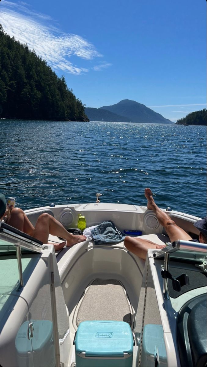 two people lounging on the back of a boat with their feet up in the water