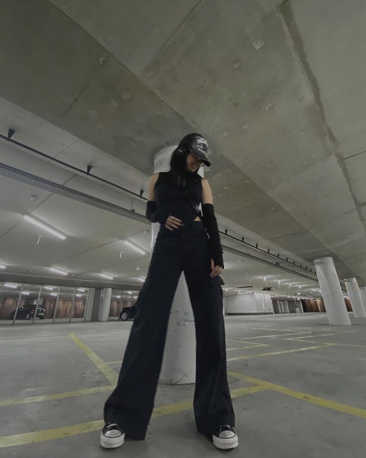 a woman standing in an empty parking garage with her hand on her hip wearing a helmet