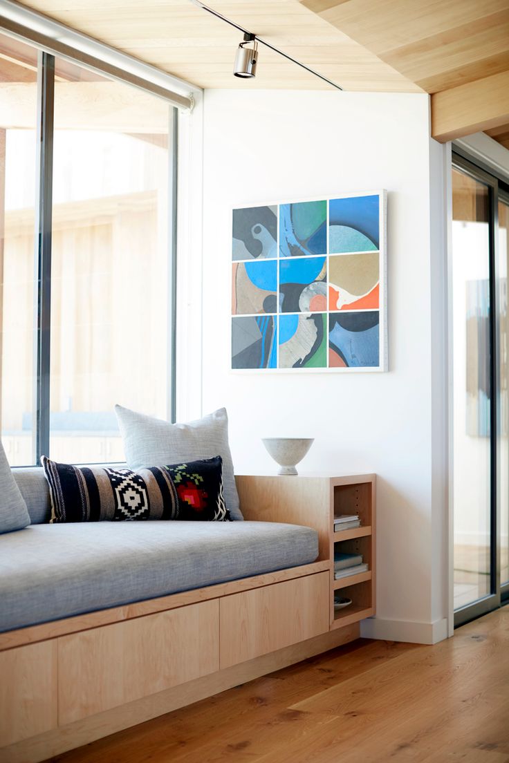 a living room filled with furniture next to large glass windows and wooden flooring on the walls