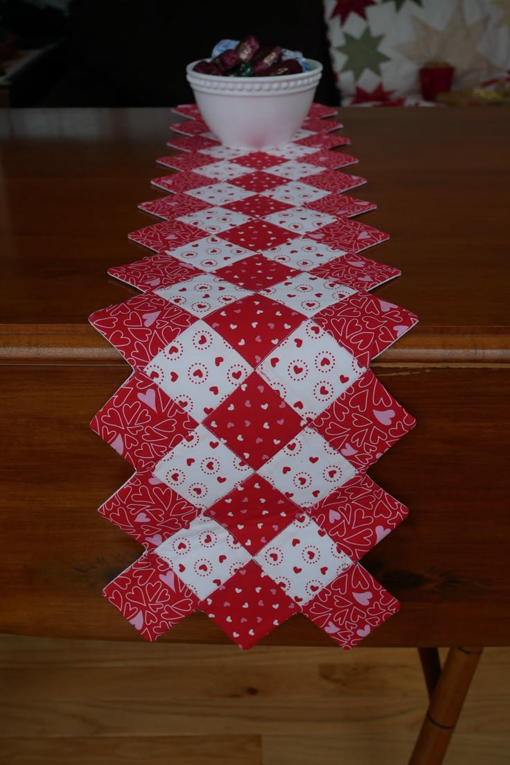 a red and white table runner on top of a wooden table