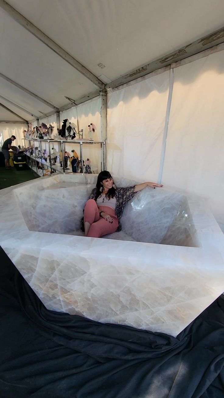 a woman is sitting in an enormous piece of white material inside a tented area