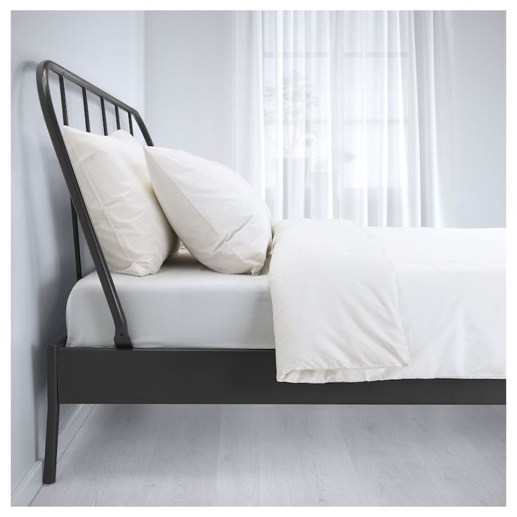 a bed with white sheets and pillows on top of it in a room next to a window