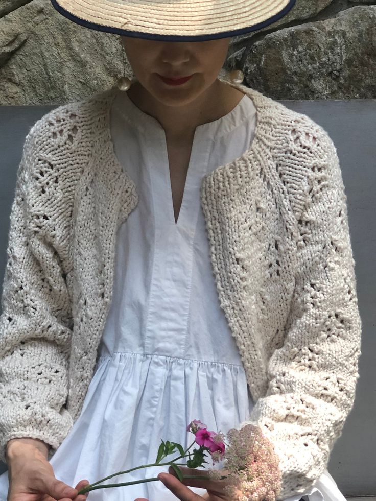 a woman in a white dress and hat holding flowers