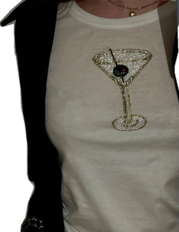 a woman wearing a white t - shirt with a martini glass on the front and black sleeves