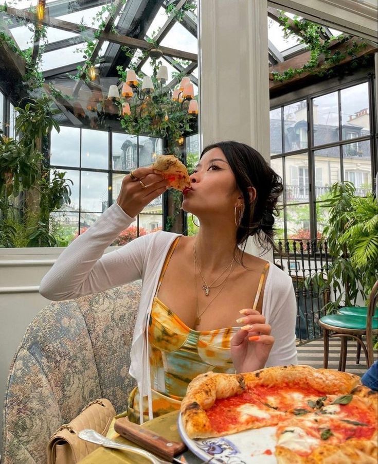 a woman sitting at a table eating pizza