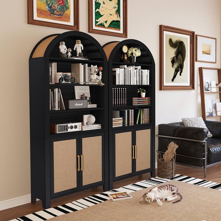 a living room with two black bookshelves in the middle and pictures on the wall