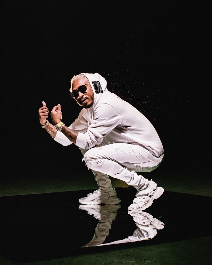 a man in white suit and sunglasses riding a skateboard on black ground with dark background