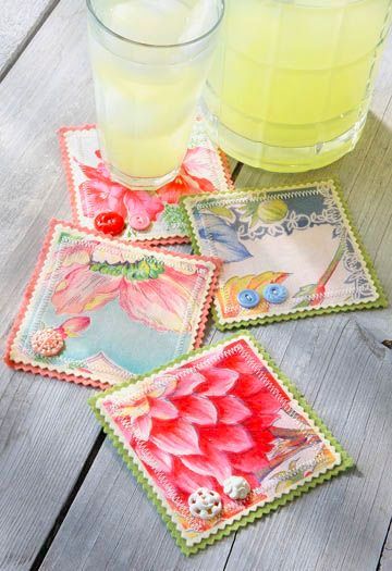 four square coasters with flowers on them next to a glass of lemonade and a drink