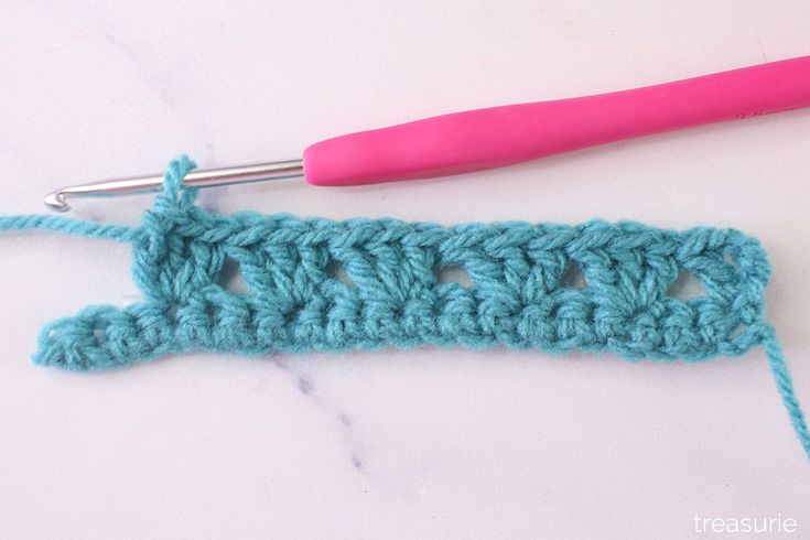 the crochet stitch is being worked on by a pink handled crochet hook