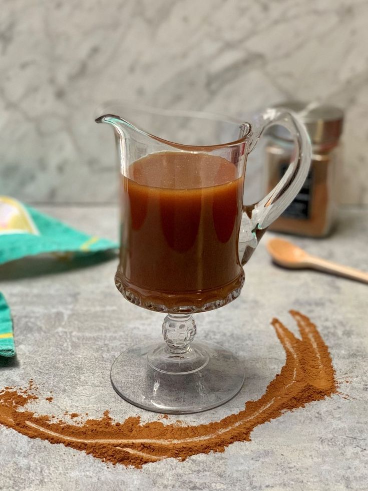 a pitcher filled with liquid sitting on top of a counter next to spices and utensils