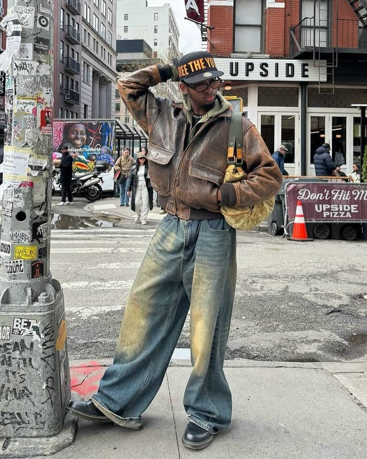 Vintage Vibe 🍩 How about his color? 📸 @knawtkai 🇺🇸 🧢Cap : free the youth 👔Hoodie : trendtvision 👞Shoes : dr.martens 👜Bag : louis vuitton Embodying the vintage vibes of American streets, this man’s outfit exudes timeless coolness. The combination of the vintage brown leather jacket and washed baggy jeans sets the tone, while the ‘Trendtvision’ khaki zipped hoodie and black printed shirt add depth to the ensemble. Elevating the look further, the ‘Dr. Martens’ black boots and ‘Free the Y... Hoodie With Leather Jacket Outfit, Brown Jadon Dr Martens Outfit, Styling Boots Men, Brown Martens Outfit, Dr Martens Boots Outfit Men, Vintage Hoodie Outfit, Vintage Brown Leather Jacket Outfit, Brown Leather Jacket Outfit Men, Outfit With Brown Boots