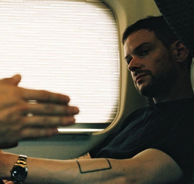 a man sitting on an airplane with his arm wrapped around another person's wrist