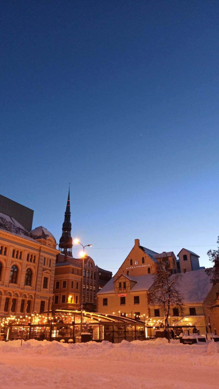 an old building is lit up at night in the snow with lights shining on it