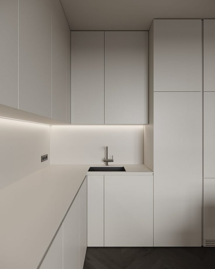 an empty kitchen with white cabinets and black counter tops is seen in this image from the side