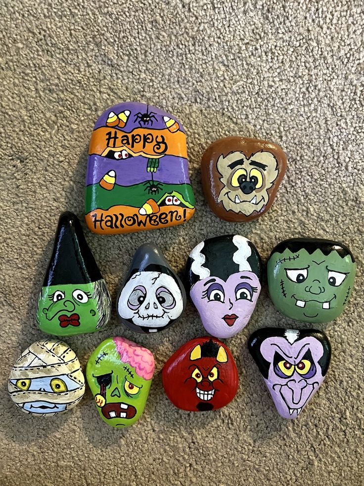 there are many painted rocks on the floor with happy halloween faces and words written on them