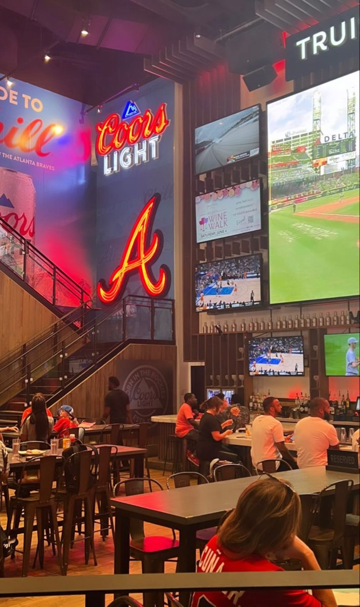 the inside of a baseball stadium with people sitting at tables and televisions on the walls