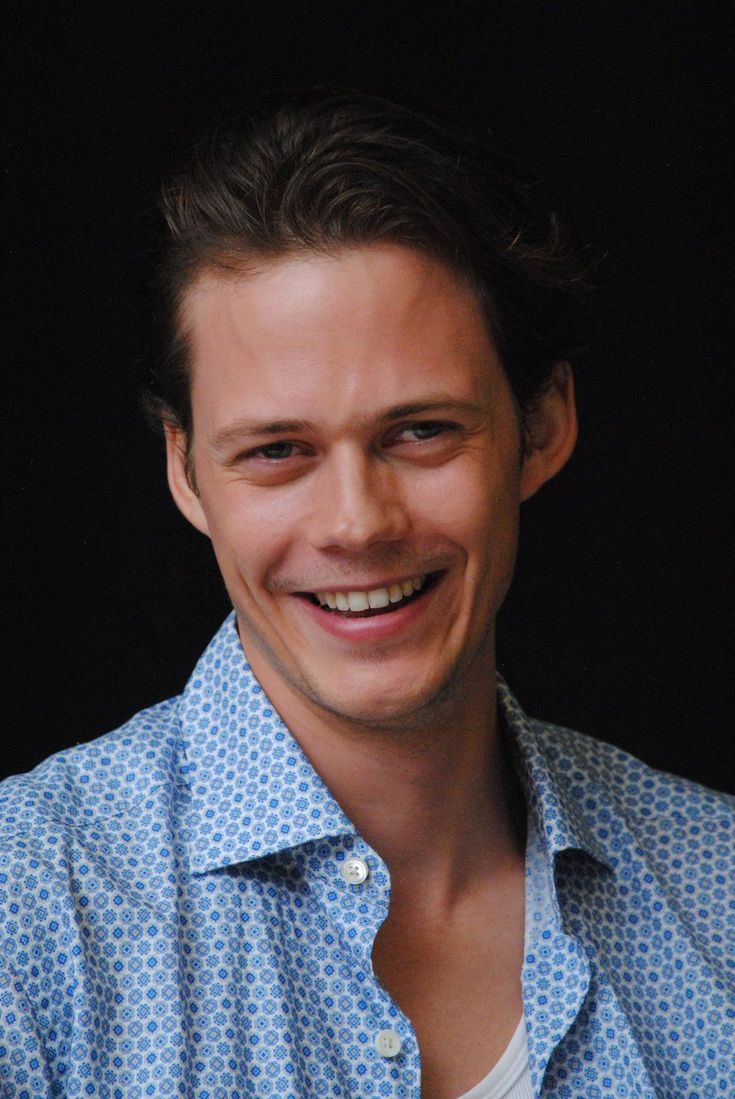 a man smiling and wearing a blue shirt