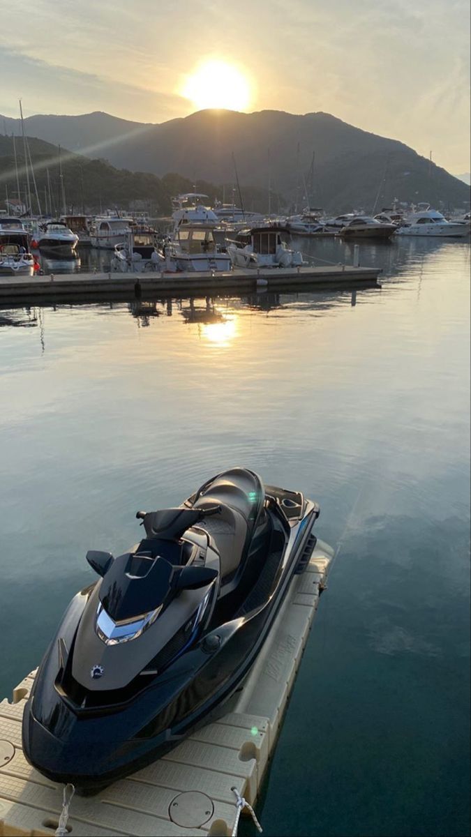 a boat is docked in the water near some docks and boats at sunset or dawn