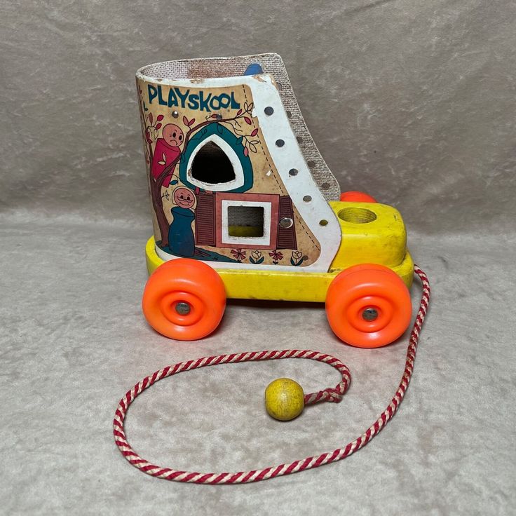 a yellow toy train with orange wheels and an orange ball