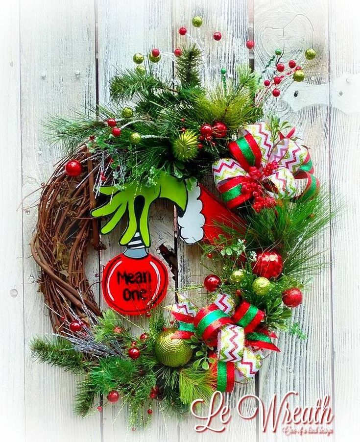 a christmas wreath is hanging on a white wooden wall with ornaments and decorations around it