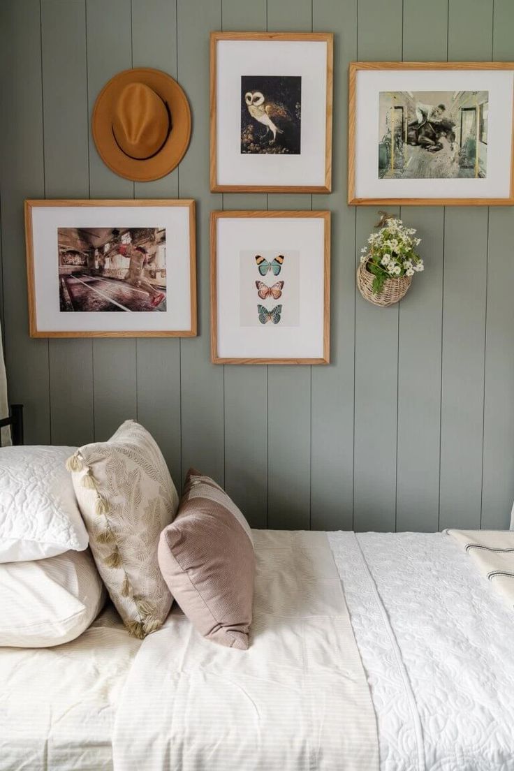 a white bed topped with pillows and pictures on the wall