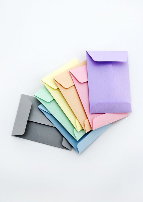 several different colored envelopes sitting next to each other on a white surface with one opened and the other closed